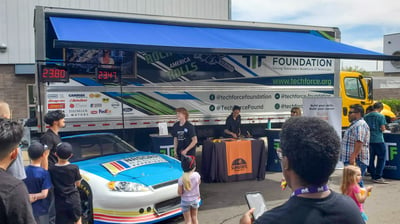 Students participating in STEM activities outdoors in front of TechForce's STEM Career Center mobile exhibit.